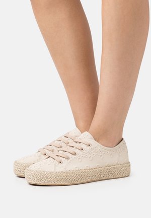 Zapatillas de lona beige con patrones intrincados de ojales, puntera redonda y suela intermedia de yute trenzado. Con cierre de cordones y superficie texturizada.