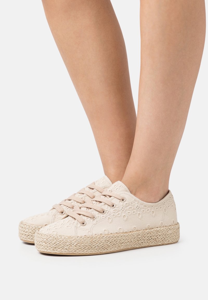 Baskets en toile beige avec des motifs d'œillets complexes, bout arrondi et semelle intermédiaire en jute tissé. Dotées d'une fermeture à lacets et d'une surface texturée.