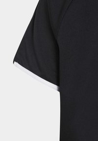 Zwart sportshirt met korte mouwen, uitgevoerd in een gestructureerde stof en met een witte rand langs de mouwranden.