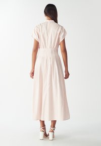 Heled roosade triipudega maxi kleit lühikeste varrukatega, kogutud talje ja voolav seelik. Kombineeritud valgete plokk-kanda sandaalidega.