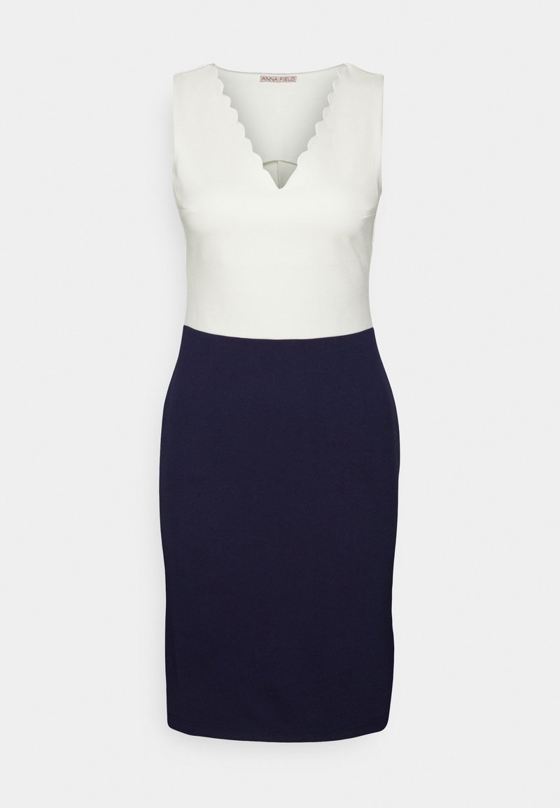 Robe sans manches avec un haut blanc à col en V festonné et une jupe crayon ajustée bleu marine foncé en bas.