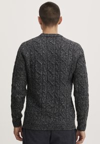 Tamsiai pilkas kabelinis megztinis su apvaliu iškirpimu, struktūrizuota medžiaga ir raukšlėtomis rankovėmis bei apačia. Savyjebūdingas reguliarus siluetas ir sudėtingas raštas.