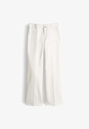 Witte high-waist wijde jeans met knoop aan de voorkant, riemlussen en opvallende zakken aan de voorkant op een witte achtergrond.