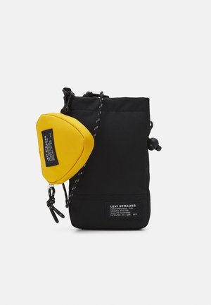 Schwarze Stofftasche mit Kordelzugverschluss und vorderem Etikett; verfügt über eine abnehmbare gelbe Tasche in Form eines Dreiecks.