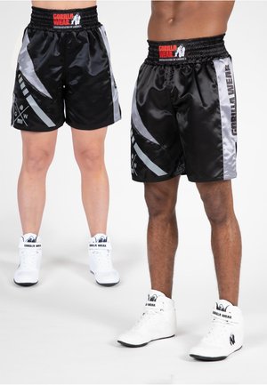 Shorts en satin noir avec des accents gris et un motif géométrique ; taille élastique avec le logo "Gorilla Wear". Associés à des baskets montantes blanches.