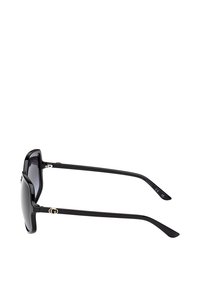 Zwarte zonnebril met een geometrisch montuur en glazen met verloop. Voorzien van gouden logo-accenten op de pootjes. Slank design met een glanzende afwerking.