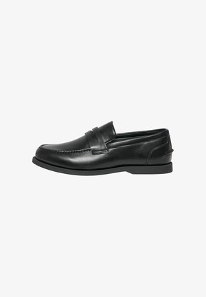 Mocassin penny en cuir noir avec couture moc toe et talon bas, présenté de profil sur fond blanc.