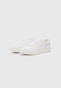 Sneaker bianche in materiale sintetico, con una texture liscia, punta tonda, suola piatta e un logo discreto sul lato.