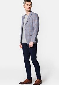 Szary marynarka w kratę z niebieskimi i czerwonymi liniami, noszona na jasnoszarym koszuli, połączona z granatowymi spodniami i brązowymi skórzanymi butami.