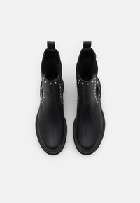 Black leather ankle boots with elastic sides and metallic studs along the outer edge. Flat sole and pull tab at the back for easy wear.