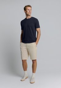 Marine crew-neck t-shirt, beige knielange shorts en lichte sneakers; casual pasvorm met een gestructureerde afwerking van het t-shirt.