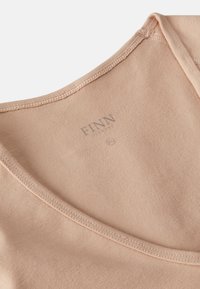 Beige cotton top with a rounded neckline, featuring a smooth texture and subtle stitching details. Brand label "FINN" visible inside.