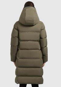 Long manteau rembourré en vert olive avec une capuche. Présente des coutures horizontales, une poche zippée et une finition lisse et imperméable.