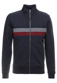 Felpa con zip di colore blu navy con colletto alto. Presenta strisce orizzontali bianche e rosse sulla parte anteriore. Tessuto morbido e texture.