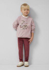Light pink sweatshirt with a swan design, paired with burgundy trousers and white sneakers. Soft texture, casual fit, and sequined details.