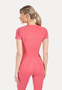 Rosa atletisk topp med kort ärm och rund halsringning, matchad med högmidjade leggings med slät textur och åtsittande design.