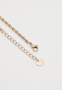 Roségoldene Kette mit ineinandergreifenden Gliedern, ausgestattet mit einem Karabinerverschluss und einem runden Anhänger. Glatte Oberfläche mit polierter Ausführung.