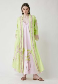 Zeleni kimono s ružičastim resicama, složen preko ružičaste haljine s vezom zelenog lišća i smeškim ravnim sandalama.