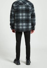 Rutig skjortjacka i ullblandning i svart, grått och vitt, med en strukturerad yta. Kombination med slim fit svarta byxor och svarta sneakers.