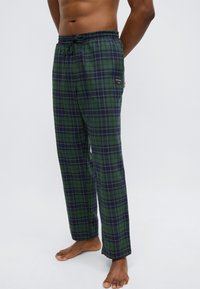 Grønne og marineblå ternede loungbukser lavet af blødt stof med elastik i taljen, snøre og sidelomme.