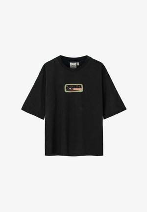 Czarny oversizeowy t-shirt z haftowanym wzorem, zestawiony z wielokolorowymi, wzorzystymi spodniami z motywem fal. Obecne srebrne dodatki biżuteryjne.