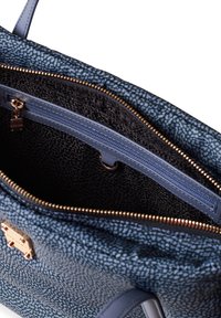 Interno di una borsa a tracolla blu con texture, che mostra una tasca con zip, rivestimento nero a contrasto e dettagli in oro sulla zip. Presenta manici doppi.