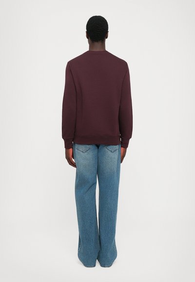 Maroon sweatshirt with crew neckline and ribbed cuffs, paired with light blue wide-leg jeans featuring a faded texture and back pocket detailing.