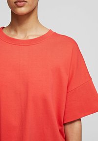 Koralfarvet kortærmet t-shirt lavet af blød bomuld. Har en rund halsudskæring og afslappet pasform, med en jævn, ensartet tekstur og minimal sømdetalje.