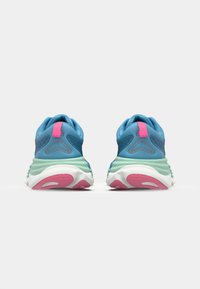 Des chaussures de sport bleues avec une semelle intermédiaire verte et des accents roses, présentant un dessus texturé et un col rembourré. La vue arrière met en avant leur forme distinctive.
