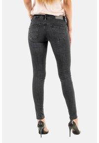 Svarta skinny jeans med hög midja, med bakfickor och subtil slitning. Bärs med svarta högklackade skor. Slätt denimtyg.