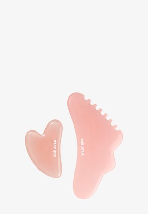 To lyserøde Gua Sha ansigtsmassageredskaber med glatte kanter og teksturerede hak, mærket "ZOË AYLA" på hvid baggrund.