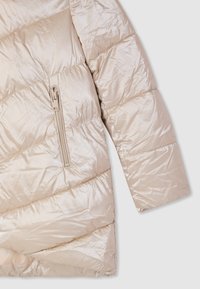 Giacca imbottita beige chiaro con design trapuntato diagonale. Presenta una tasca con cerniera laterale e una texture liscia e lucida.