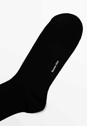 Schwarze gerippte Socke aus weichem Material mit glatter Textur und einem gedruckten Logo an der Seite. Klassisches Design mit einer runden Zehenpartie.