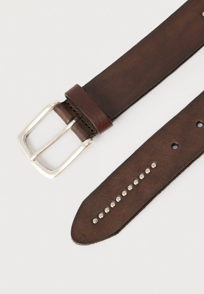 Ceinture en cuir marron foncé avec boucle rectangulaire argentée et rangée de petites clous ronds argentés près de l'extrémité pointue sur fond blanc.