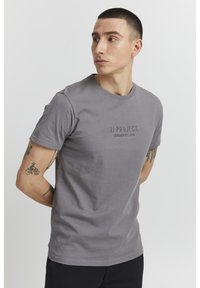 Grå bomulls t-skjorte med rund hals, med en subtil trykt logo "11 PROJECT. DENMARK EST. 2019" på brystet. Korte ermer og normal passform.