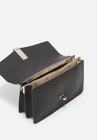 Musta nahkainen käsilaukku, jossa on teksturoitu pinta, kultaiset yksityiskohdat ja magneettiklipsi. Sisätiloissa on kaksi osastoa, joissa on vaaleanbeige vuori.