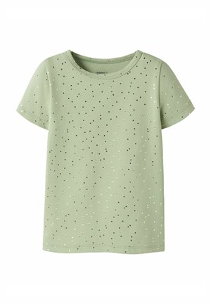 T-shirt vert clair à manches courtes avec de petits points argentés et noirs dispersés et un col rond.