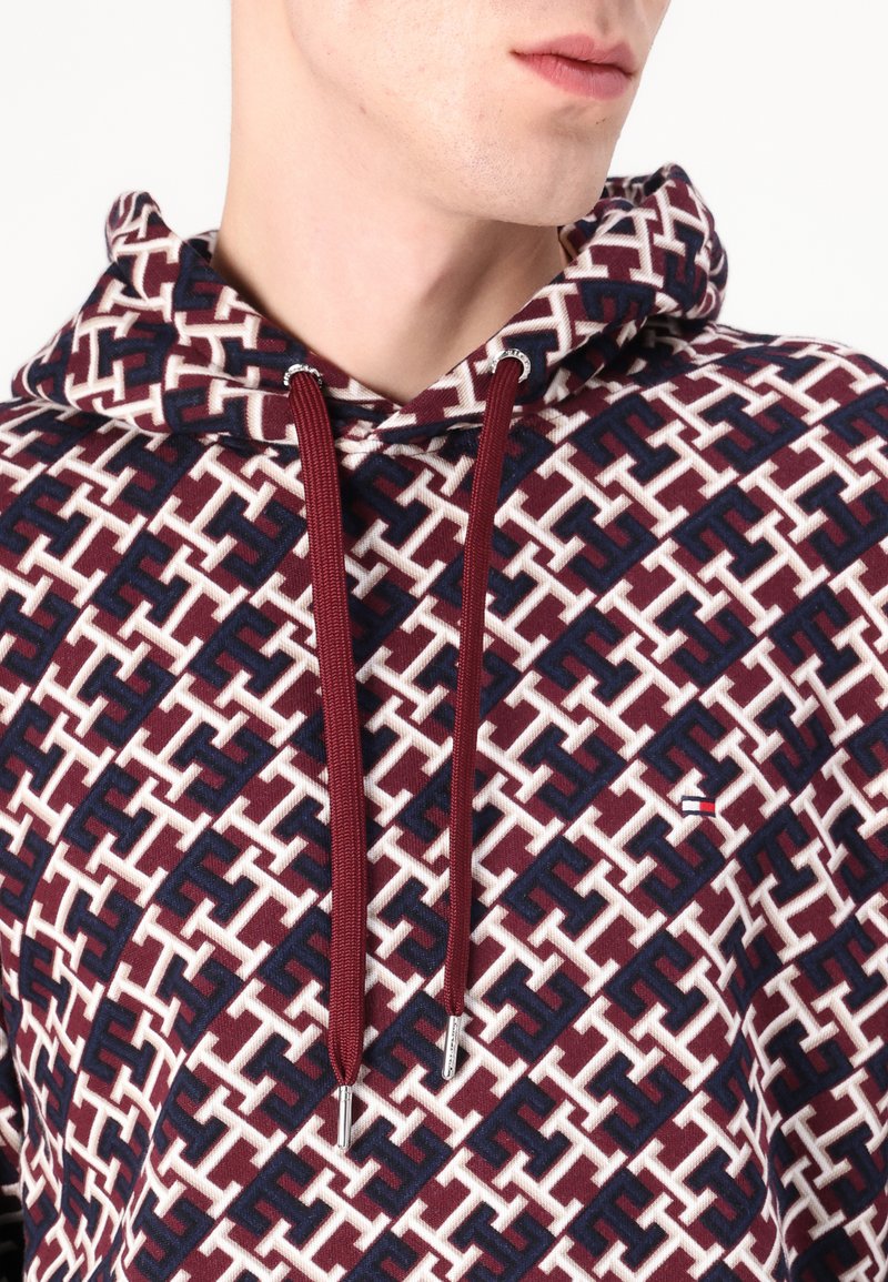 Felpa con cappuccio caratterizzata da un motivo geometrico in bordeaux, blu navy e bianco; realizzata in tessuto morbido con cordoncini e dettagli del logo.