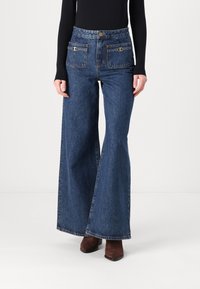 Högmidjade, vida blå jeans med två framfickor, synlig sömnad och knappstängning i midjan.