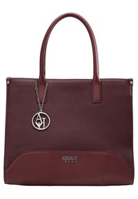 Bordowa skórzana torebka o teksturowanej powierzchni, gładkich akcentach, podwójnych uchwytach i metalowym zawieszce z logo. Na dole widoczna subtelna nazwa marki.