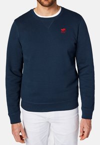 Granatowy sweter z okrągłym dekoltem, długimi rękawami, ściągaczami przy nadgarstkach i u dołu. Zawiera małe czerwone logo na lewej piersi.