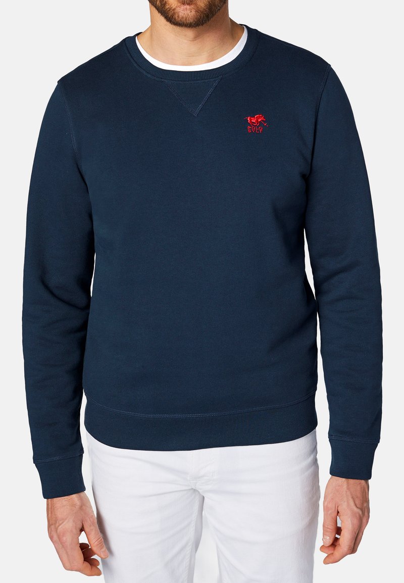 Granatowy sweter z okrągłym dekoltem, długimi rękawami, ściągaczami przy nadgarstkach i u dołu. Zawiera małe czerwone logo na lewej piersi.