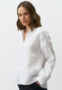 Witte linnen blouse met een kraaghalslijn, sluiting met knopen aan de voorkant en lange mouwen. Heeft een losse pasvorm en een licht gestructureerde stof.