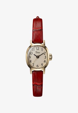 Petite montre Timex dorée avec cadran beige, chiffres noirs, aiguilles des heures et des minutes noires, et bracelet en cuir rouge.