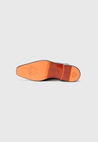 La suela de un zapato de vestir de cuero presenta un acabado negro suave con una base de goma naranja contrastante. Incluye un detalle del logo en relieve y ranuras horizontales.