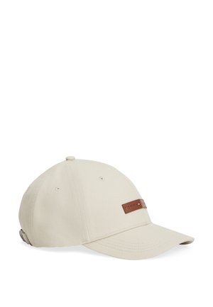 Bēšs beisbola cepure ar izliekumu un regulējamu siksnu, priekšpusē ar nelielu ādas uzlikumu ar zīmola nosaukumu.