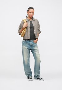 Koszula w paski na guziki, szary top na ramiączkach, jasnoniebieskie jeansy typu distressed, czarne sneakersy oraz teksturowana torebka w złotym odcieniu. Casual, luźny fason.