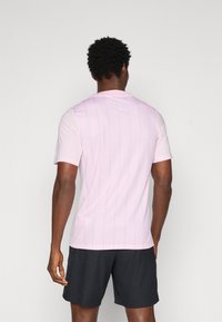 Šviesiai rožinė trumpų rankovių marškinėliai su vertikaliomis juostelėmis ir apvaliu iškirpimu, derinami su juodais tekstūriniais šortais. Prasminga medžiaga, sportiška prigludimas.