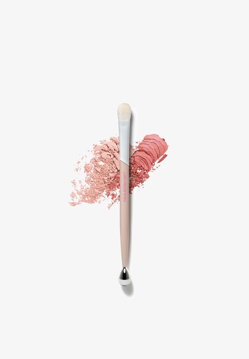 Make-upkwast met een zachte, witte harenkop, een taps toelopende beige greep en een metallic zilveren accent. Omringend roze poeder toont textuur en kleur.