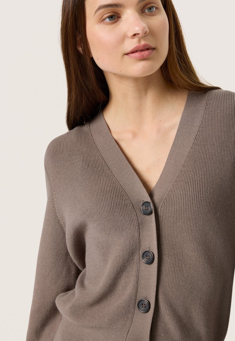 Brauner gerippter Cardigan mit V-Ausschnitt, der vier schwarze Knöpfe auf der Vorderseite hat und eine weiche Textur aufweist.